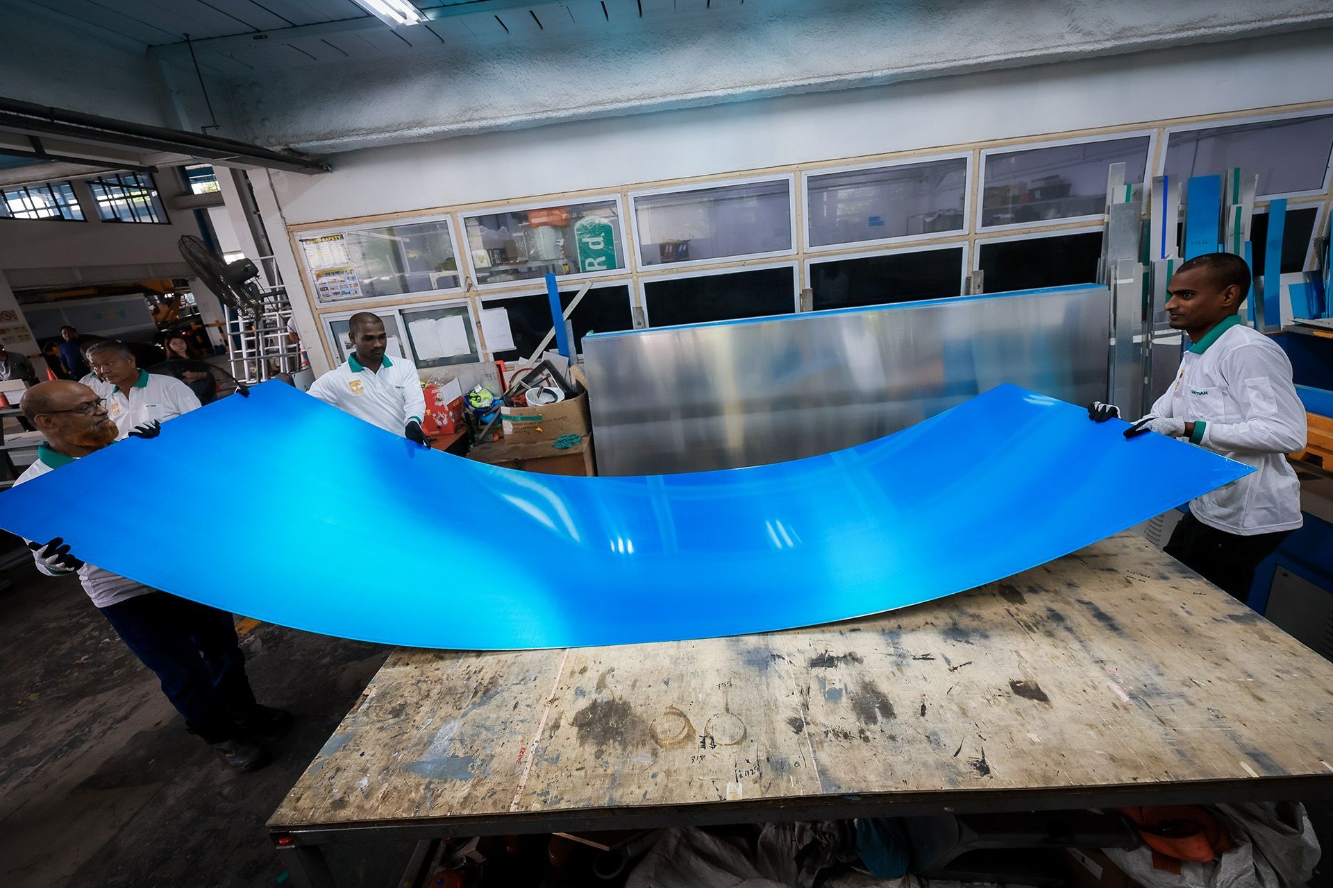 Workers carrying a large aluminium alloy sheet.