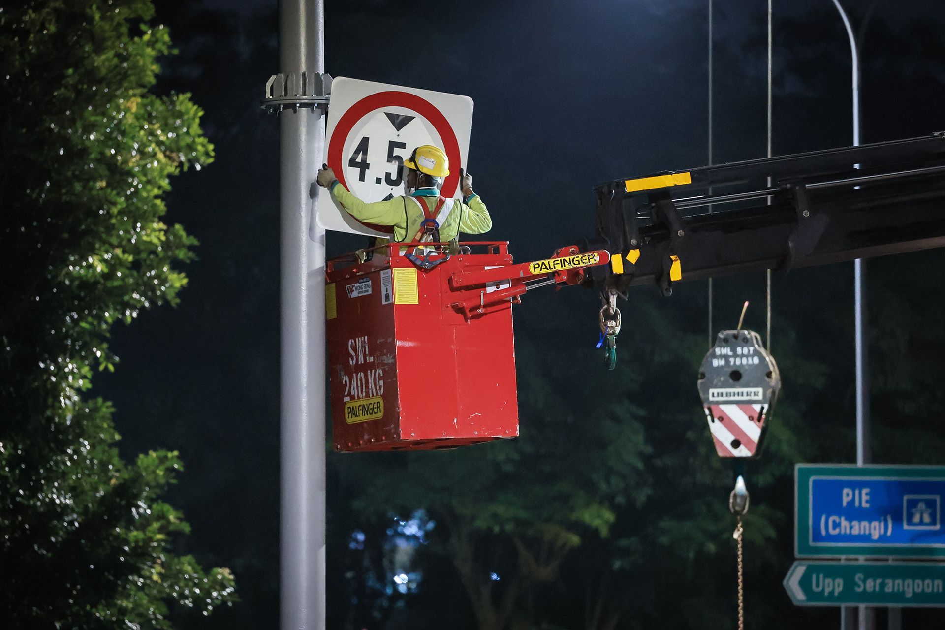 A worker fixes a height clearance sign to the gantry columns.