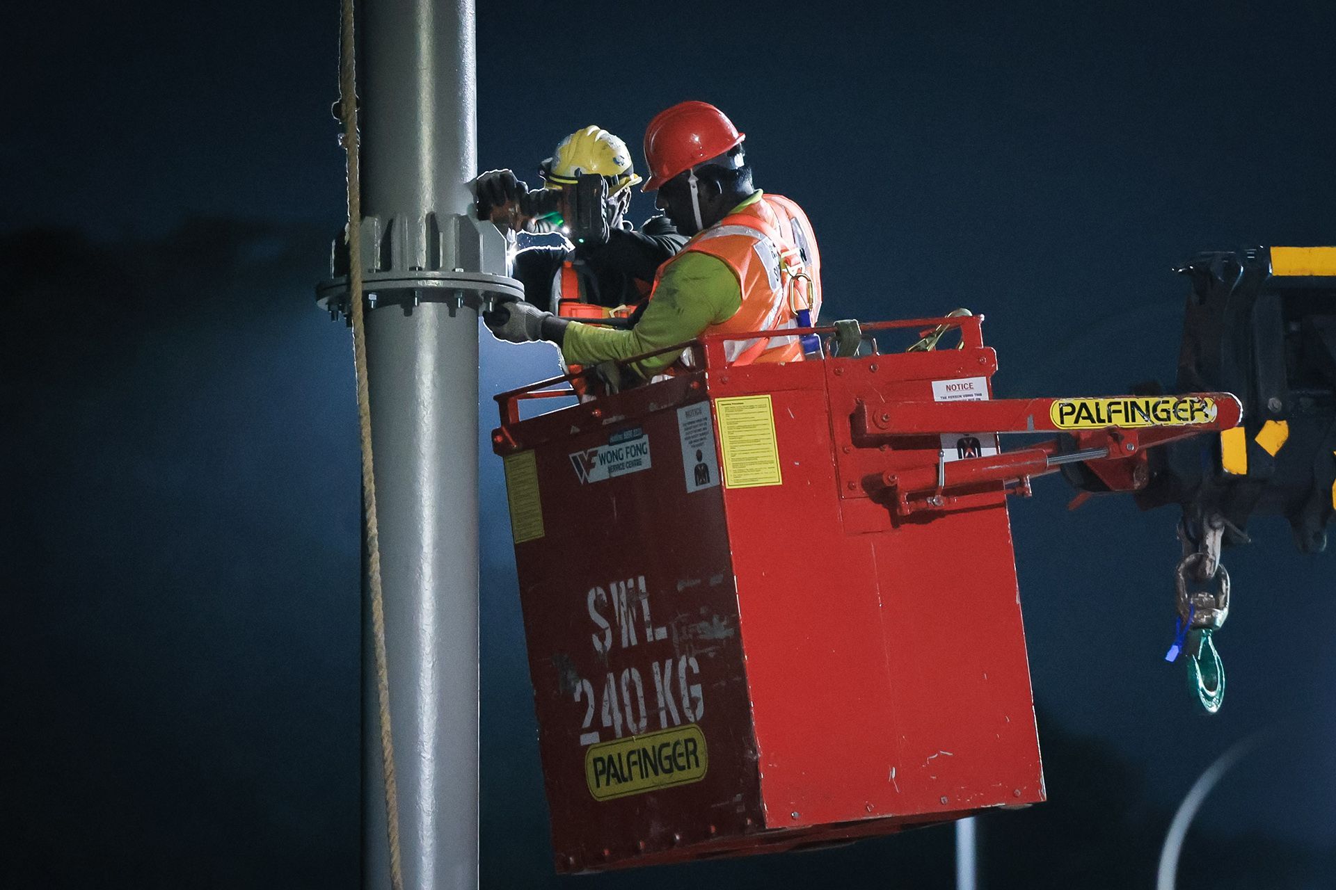 Workers secure the gantry by tightening bolts at connection points.