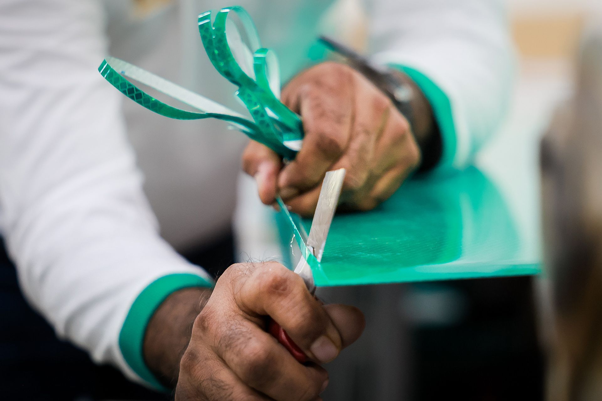 A worker uses a penknife to trim the edges of a signboard.