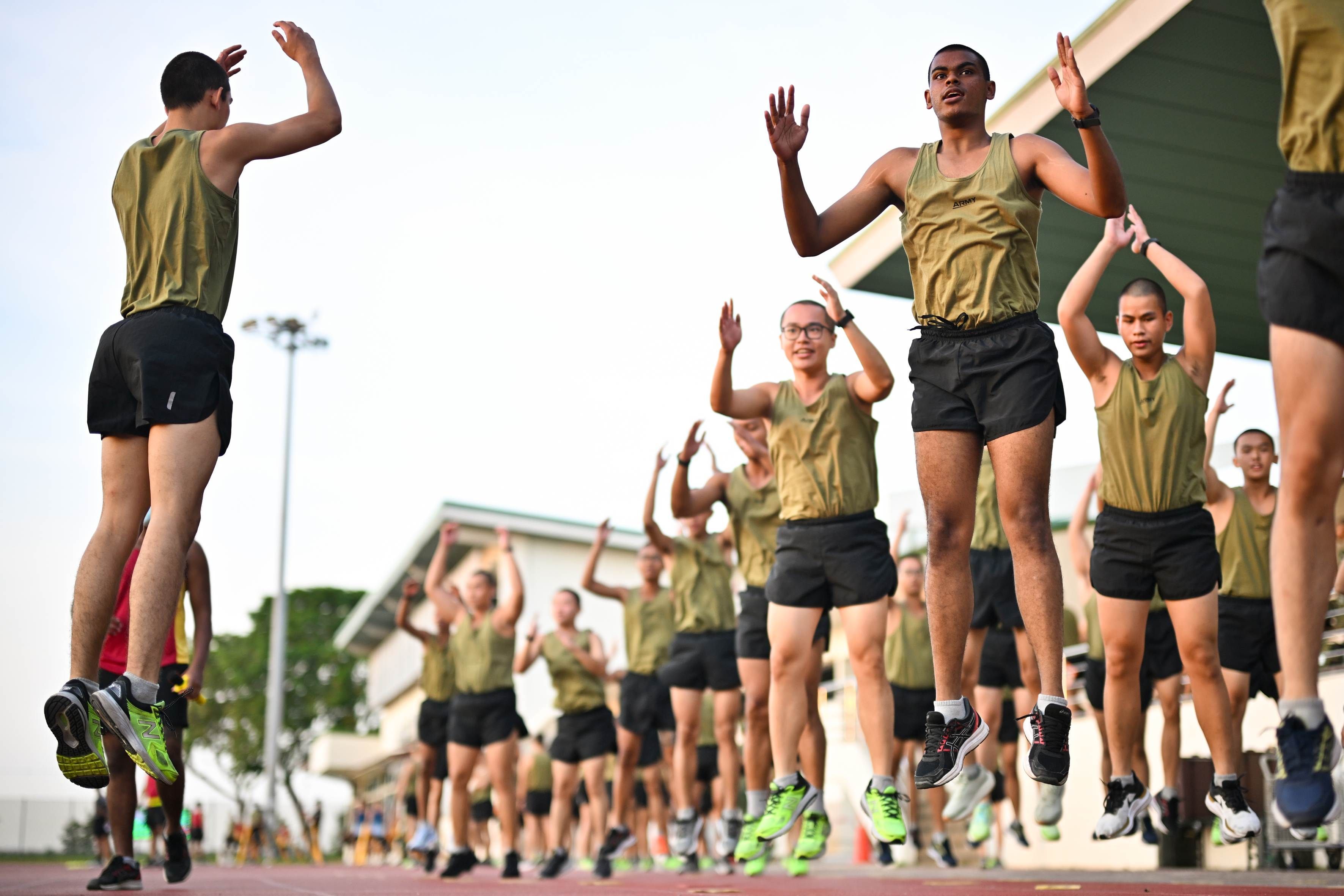 A group of men do warm up exercises at the Basic Military Training Centre on Pulau Tekong.